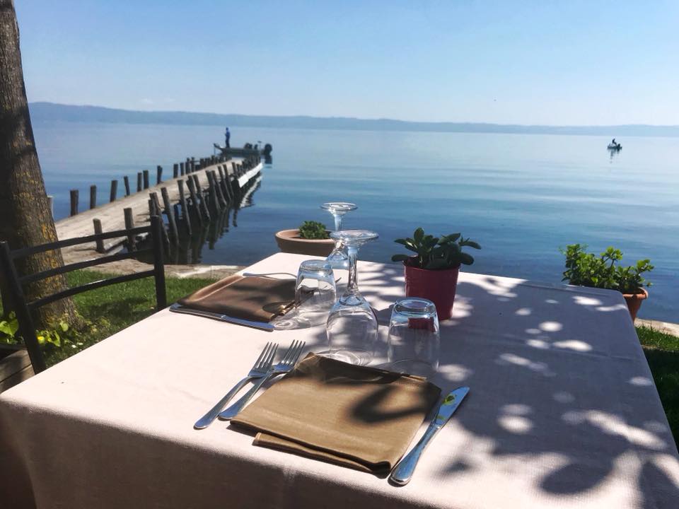 Tavolo apparecchiato all'aperto vicino a un lago.