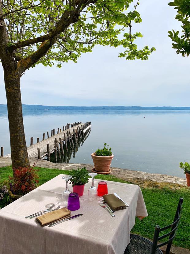 Tavolo apparecchiato all'aperto vicino a un lago.