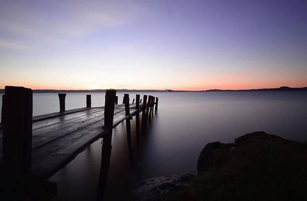 Pontile in legno su lago al tramonto.