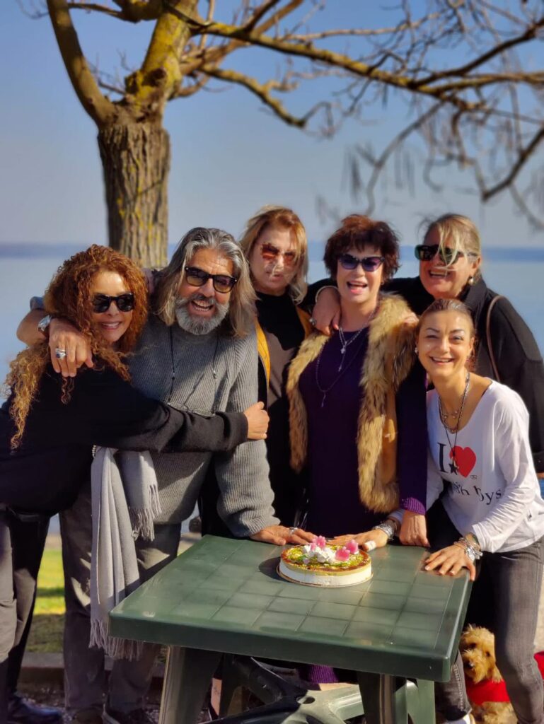 Gruppo di persone sorridenti intorno a un tavolo all'aperto.
