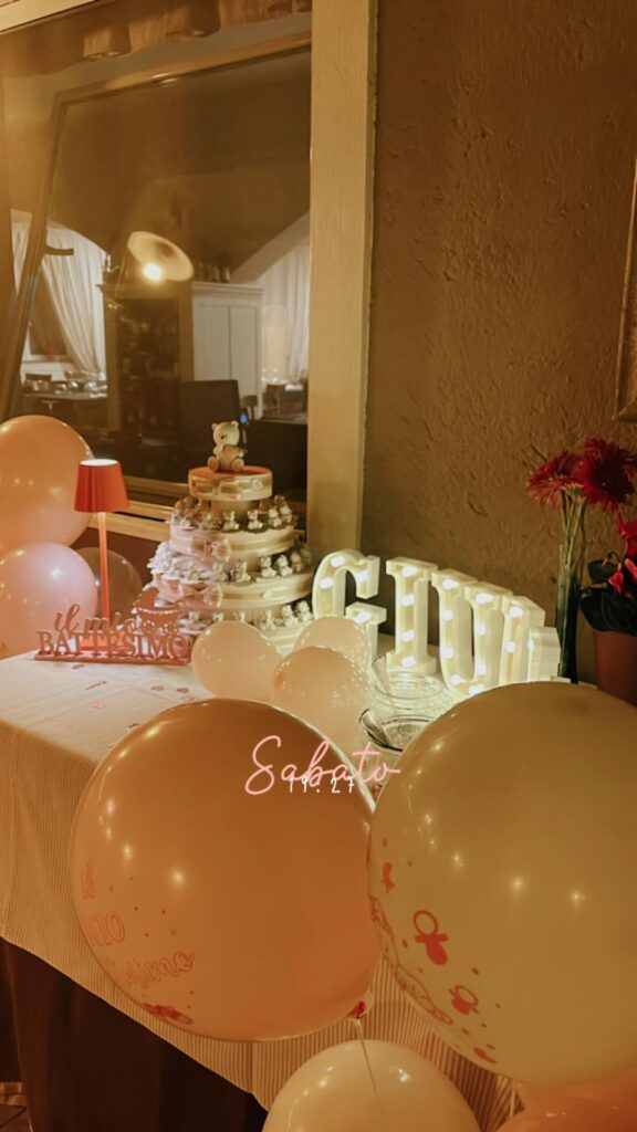 Tavolo decorato per battesimo con palloncini e torta.