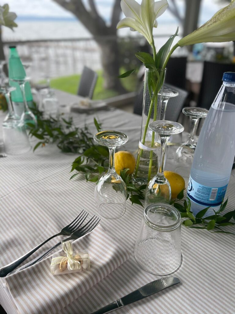 Tavola apparecchiata con fiori, bicchieri e limoni.