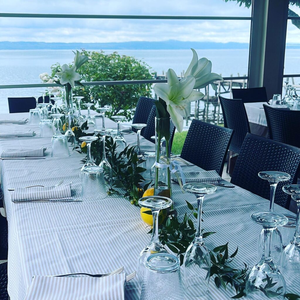 Tavola apparecchiata con fiori bianchi e vista lago.