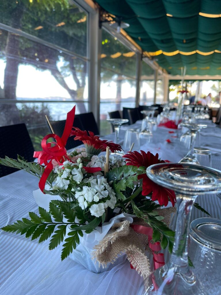 Tavola apparecchiata con fiori rossi e bianchi.