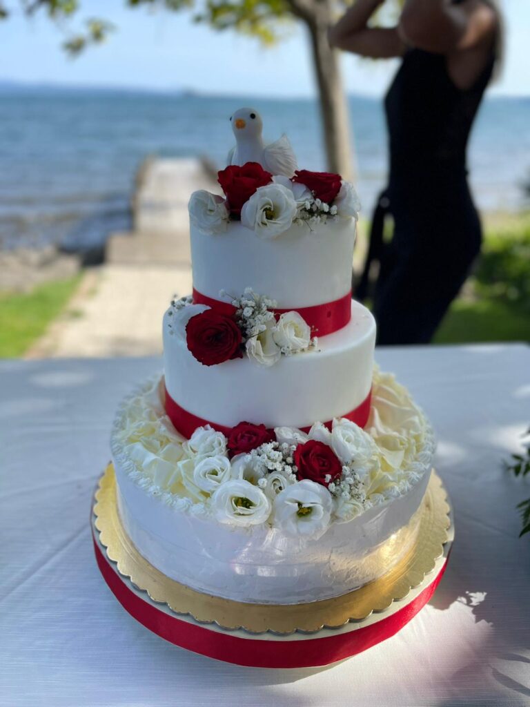 Torta a tre piani con fiori rossi e bianchi.