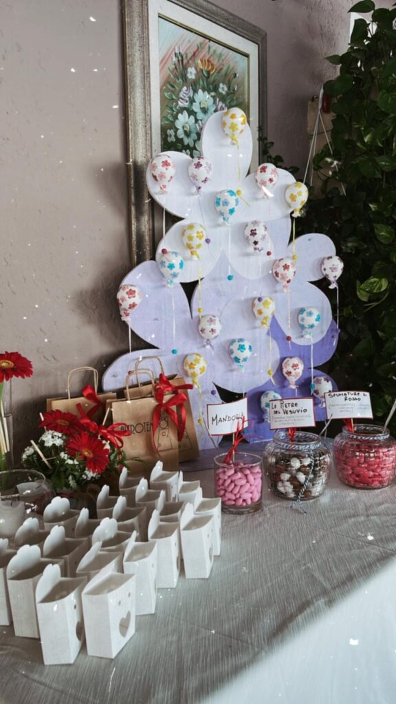 Tavolo con confetti, decorazioni floreali e scatoline regalo.