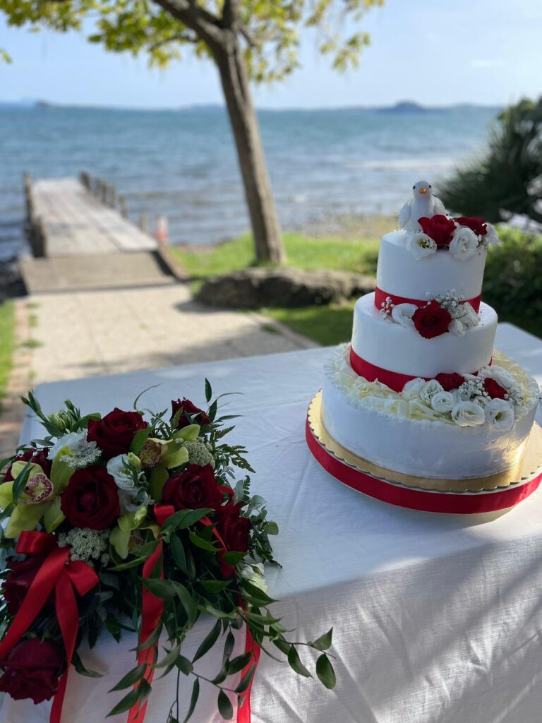 Torta nuziale e bouquet su tavolo, vista lago.