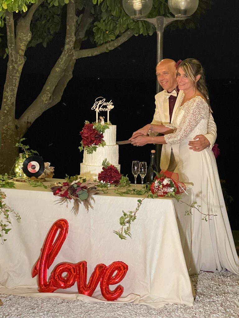 Coppia taglia torta nuziale su tavolo decorato.