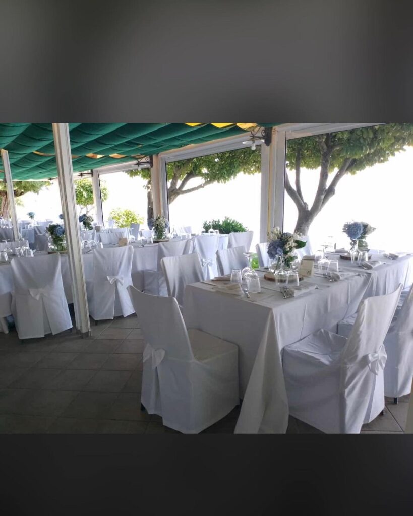 Tavoli apparecchiati con tovaglie bianche in un ristorante.