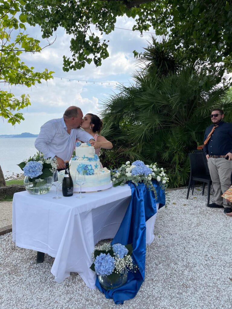 Coppia bacia davanti a torta nuziale all'aperto.