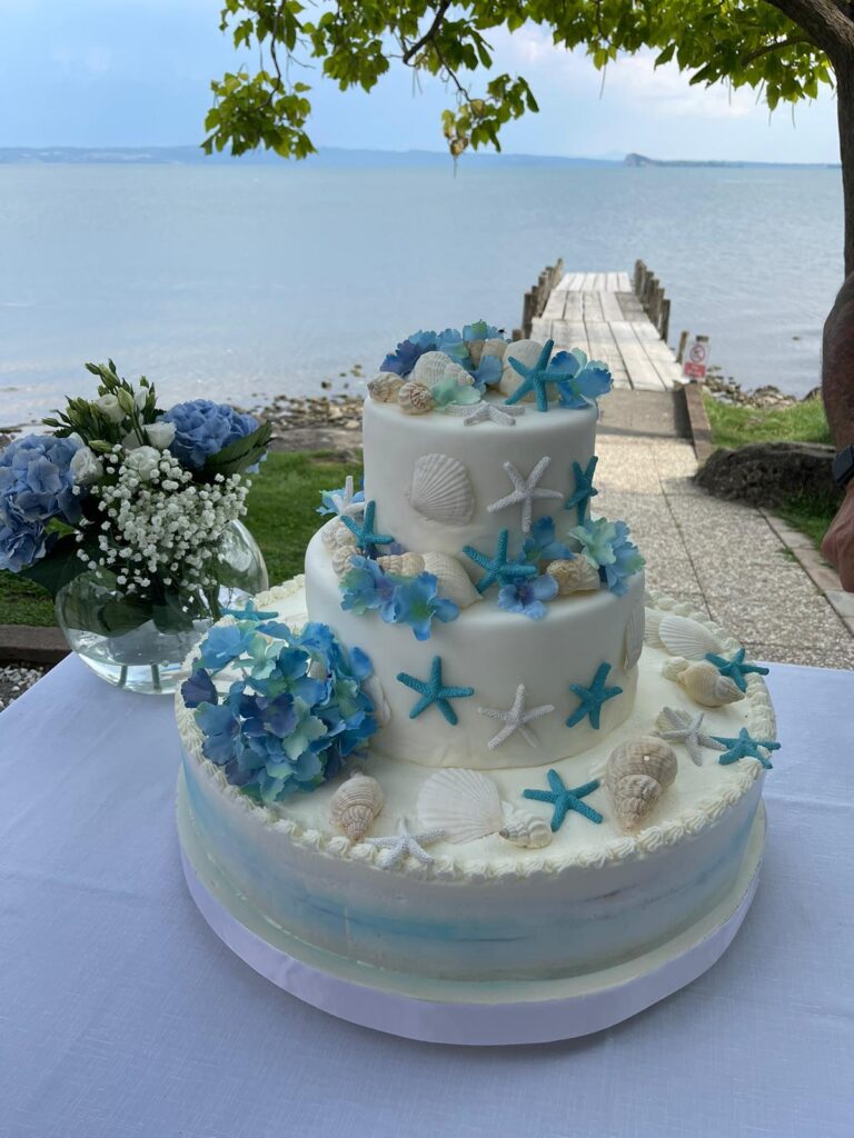 Torta decorata con conchiglie e stelle marine, vista lago.