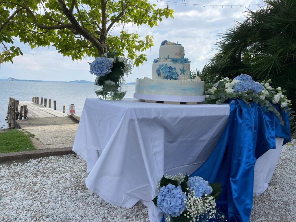 Tavolo con torta nuziale e decorazioni floreali blu.
