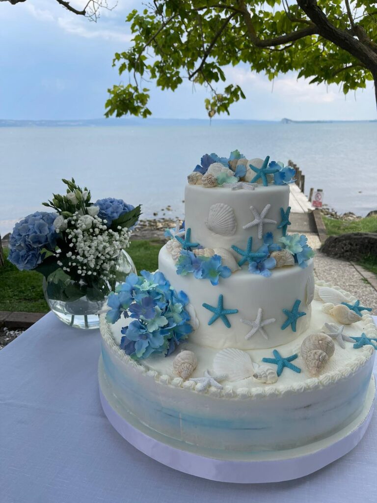 Torta decorata con stelle marine e conchiglie, vicino al mare.