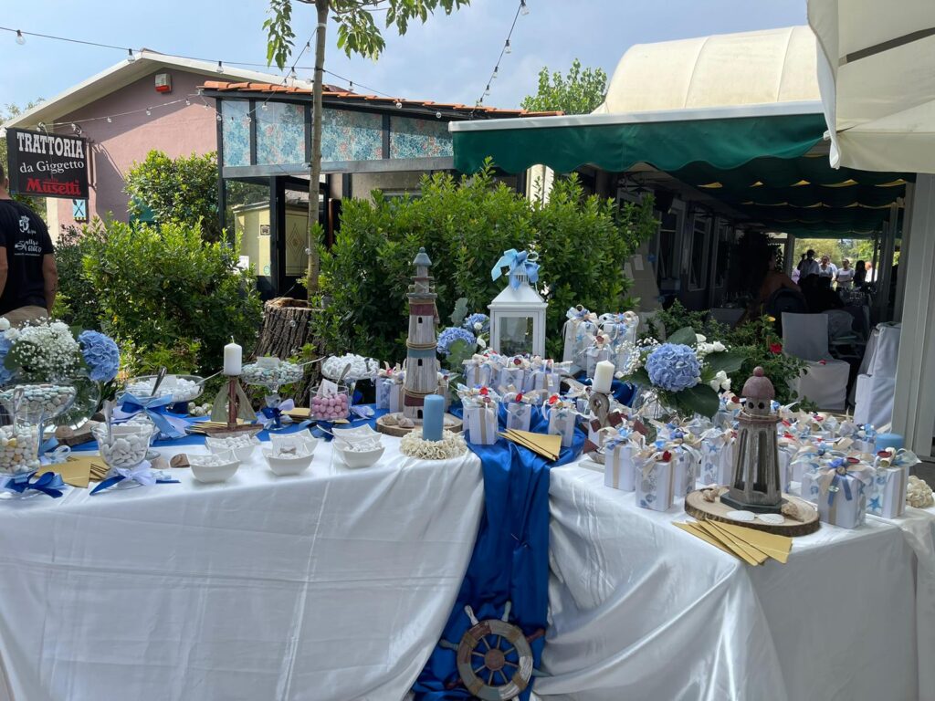 Tavolo decorato per evento all'aperto con confetti e regali.