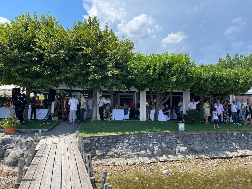 Persone riunite sotto alberi vicino a un ristorante.
