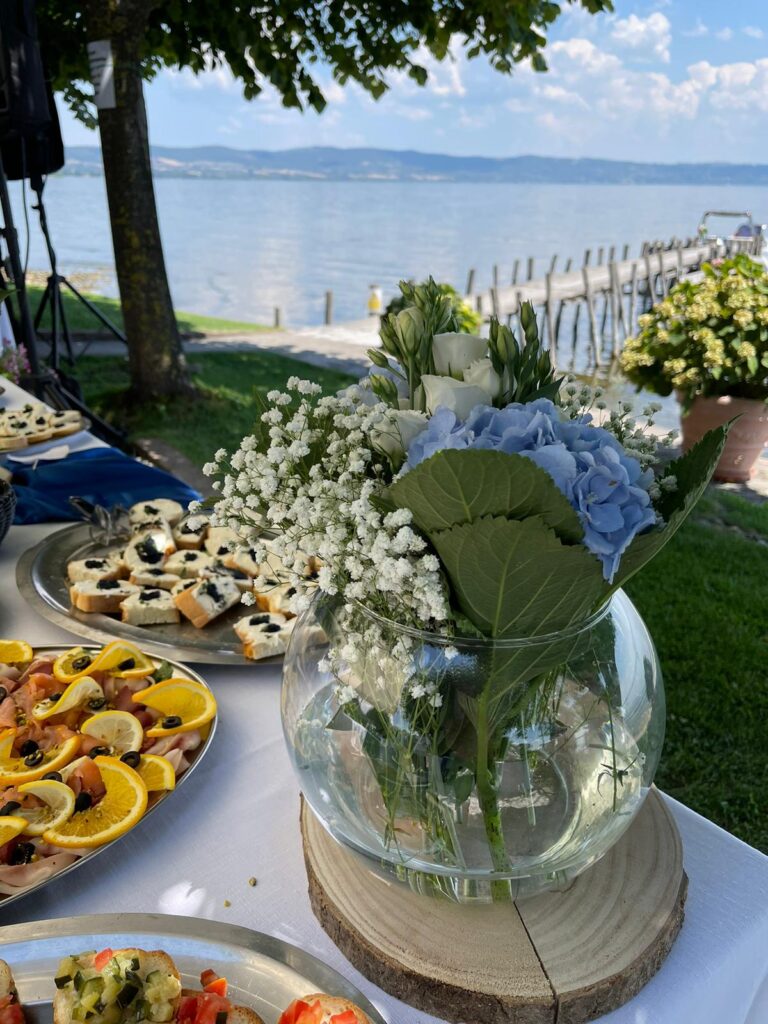 Fiori in vaso e cibo su tavolo vista lago.