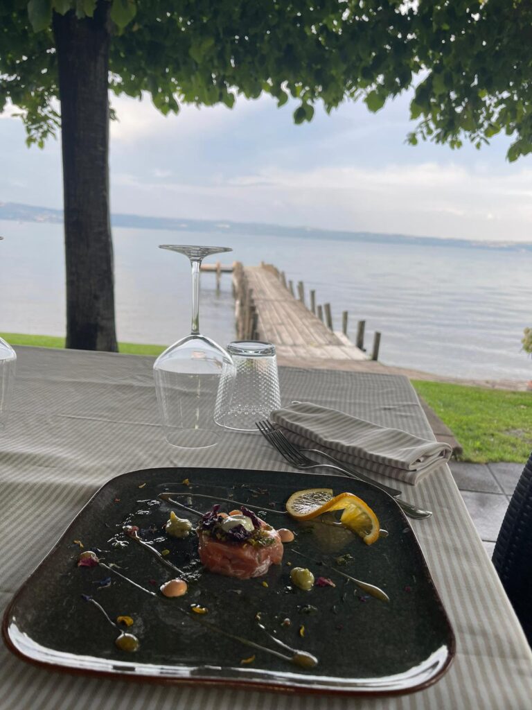 Piatto di tartare su tavolo con vista lago.