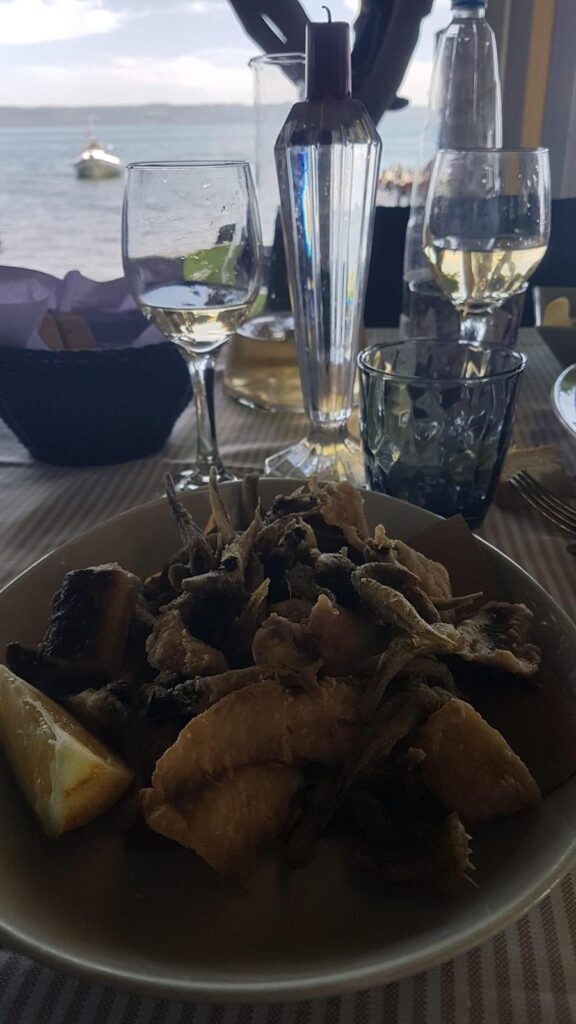 Piatto di pesce fritto con bicchieri di vino.