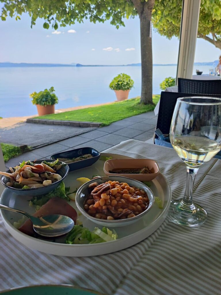 Piatto di antipasti e bicchiere di vino vicino al lago.