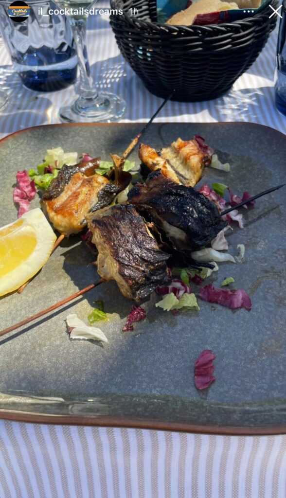 Spiedini di pesce grigliato con insalata e limone.