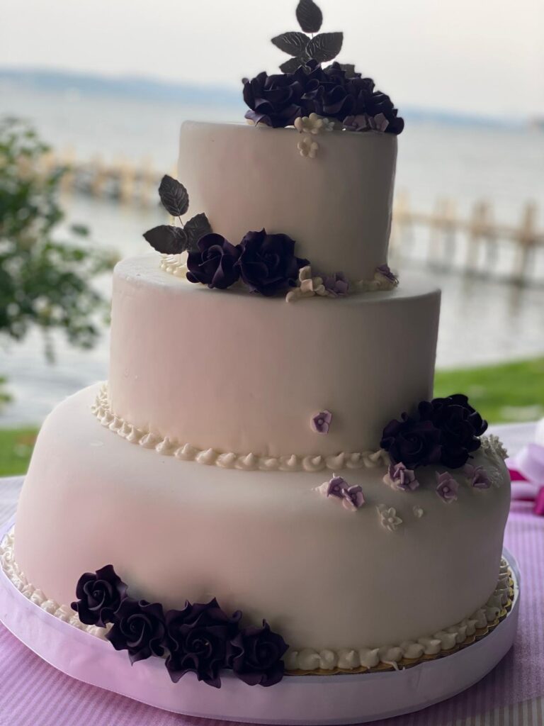 Torta nuziale a tre piani con fiori viola.