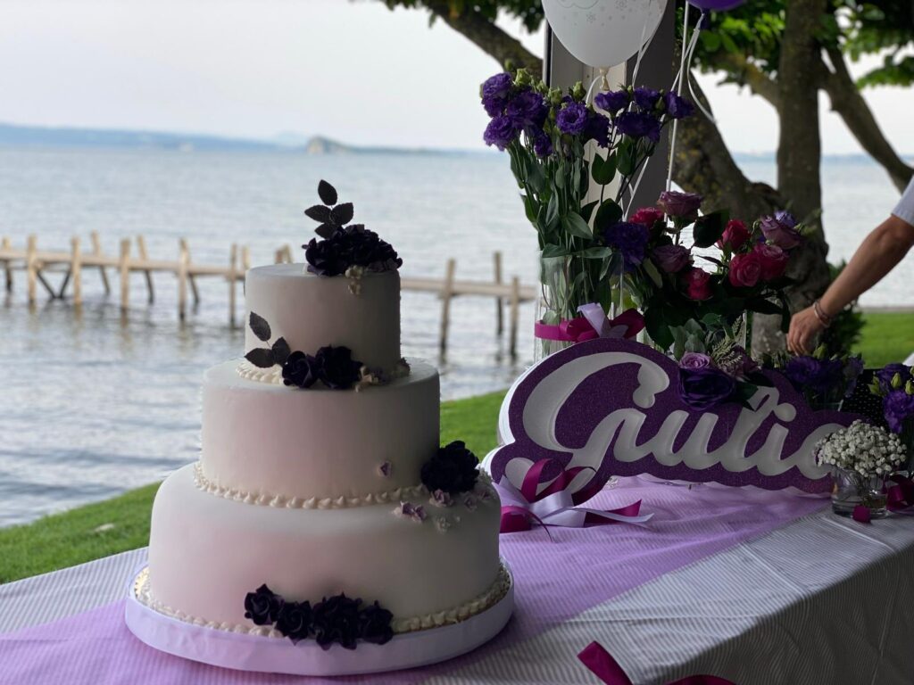 Torta nuziale a tre piani con decorazioni floreali viola.