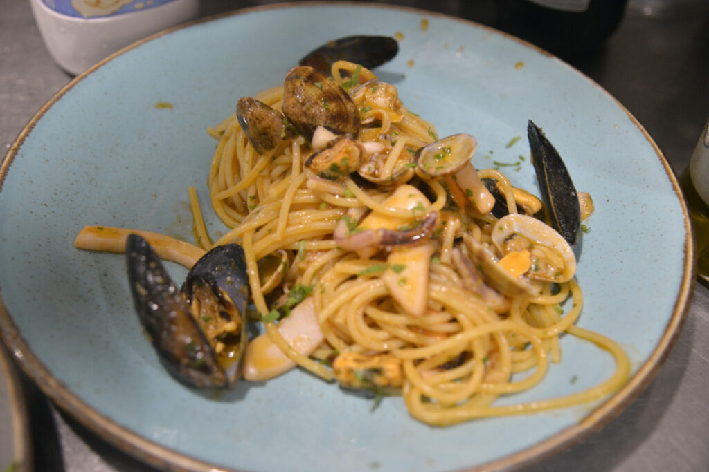 Spaghetti ai frutti di mare su piatto azzurro.