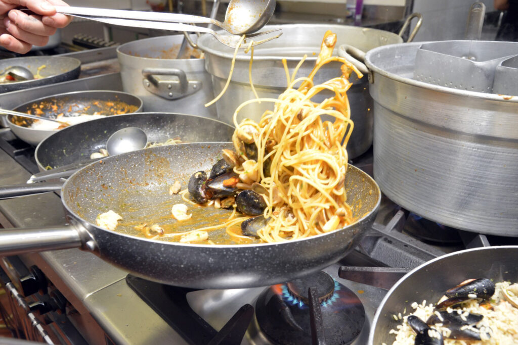 Spaghetti ai frutti di mare in padella su fornello.