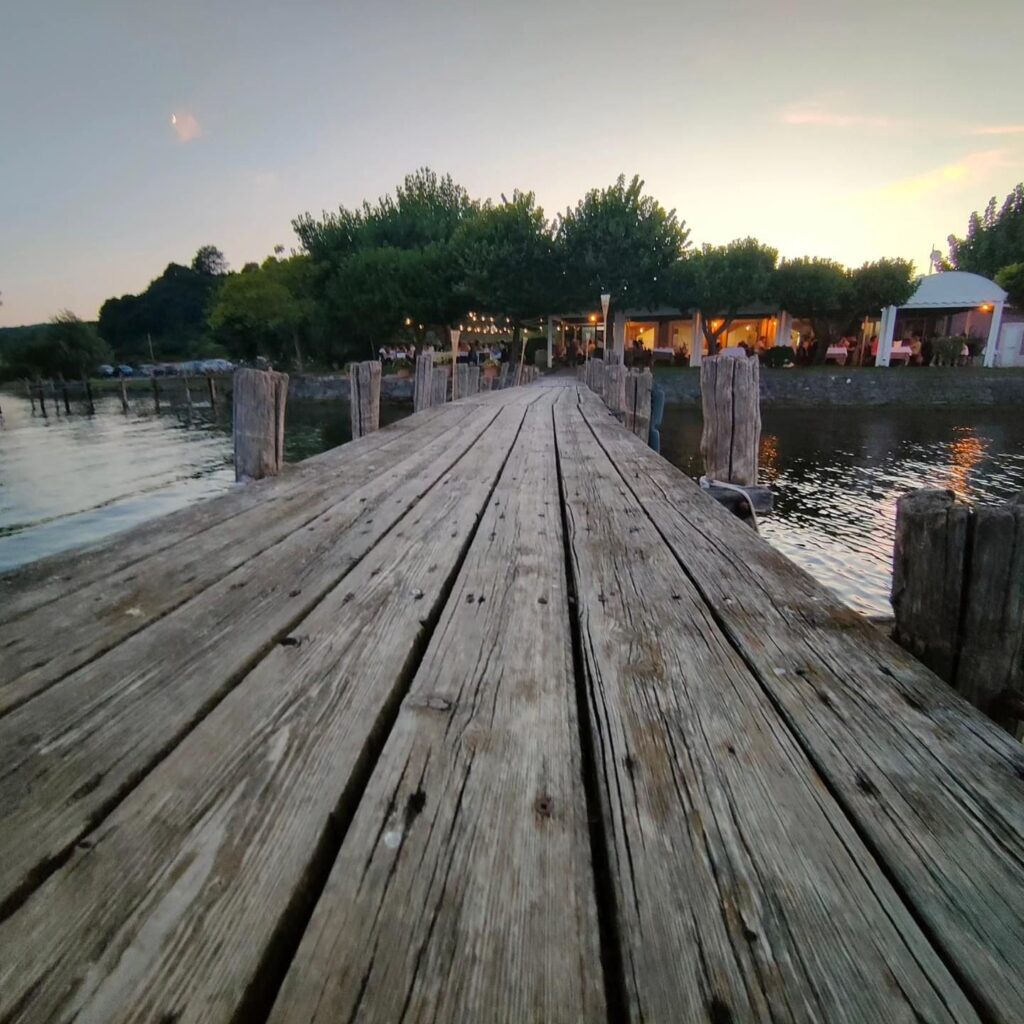 Pontile di legno al tramonto con ristorante sullo sfondo.