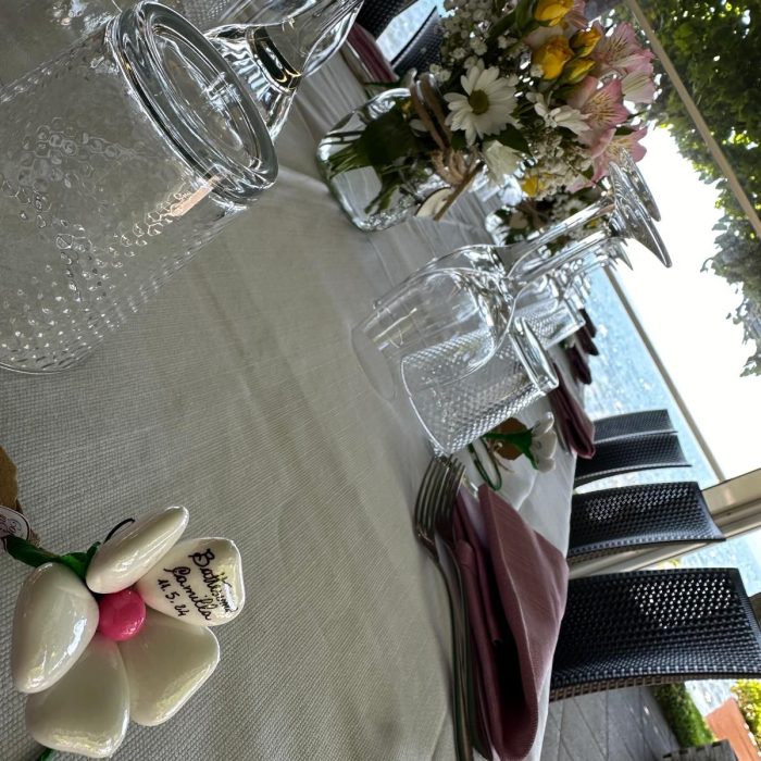 Tavola apparecchiata con fiori e bicchieri, vista lago.