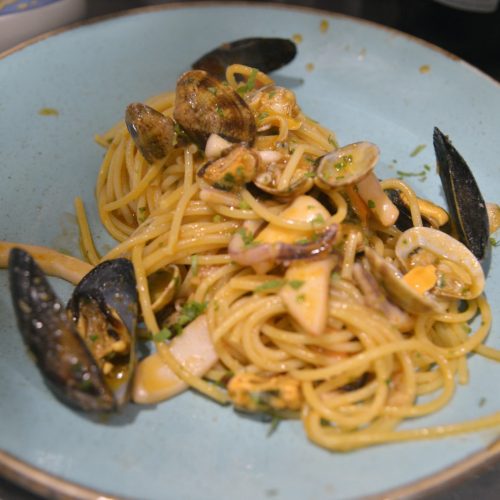 Spaghetti ai frutti di mare su piatto azzurro.
