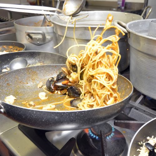 Spaghetti ai frutti di mare in padella su fornello.