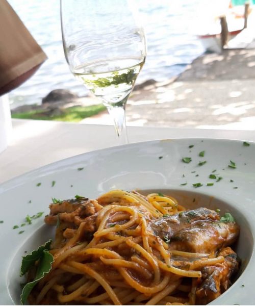 Teller Spaghetti mit Fisch und einem Glas Wein.