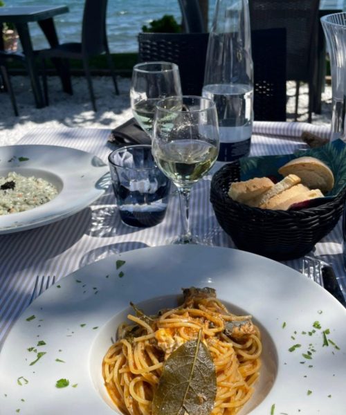 Ein Teller Spaghetti und ein Glas Wein mit Blick aufs Meer.