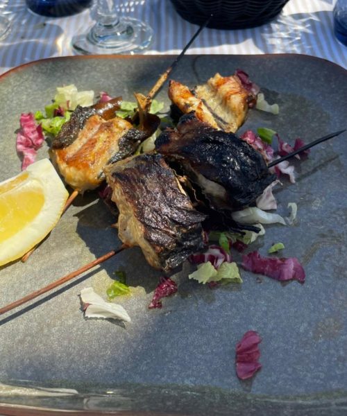 Gegrillte Fischspieße mit Salat und Zitrone.