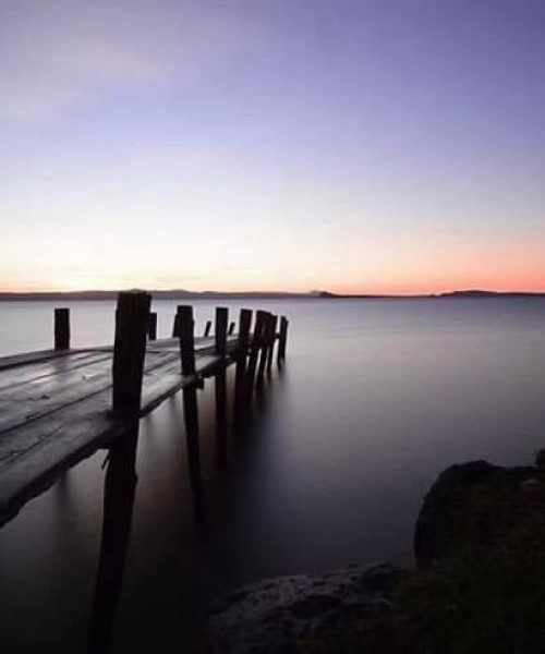 Holzsteg am See bei Sonnenuntergang.