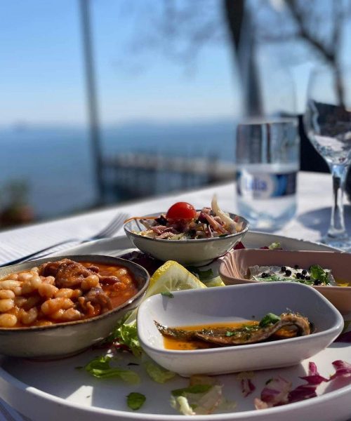 Teller mit Essen auf einem Tisch mit Meerblick.