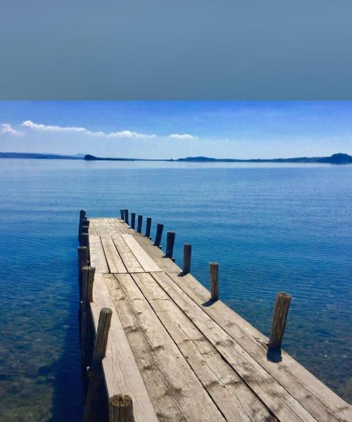 Holzsteg auf ruhigem See und klarem Himmel.